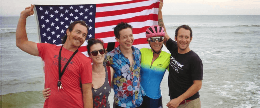 group of people smiling while holding up an American flag