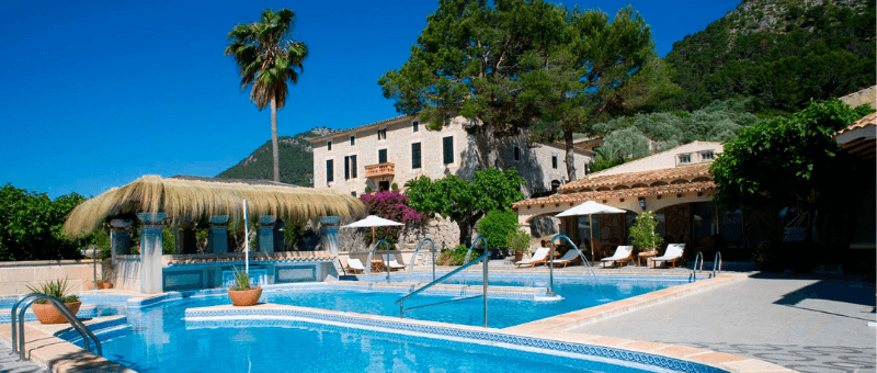 exterior view of outdoor hotel pool with manor style hotel accommodations in the background