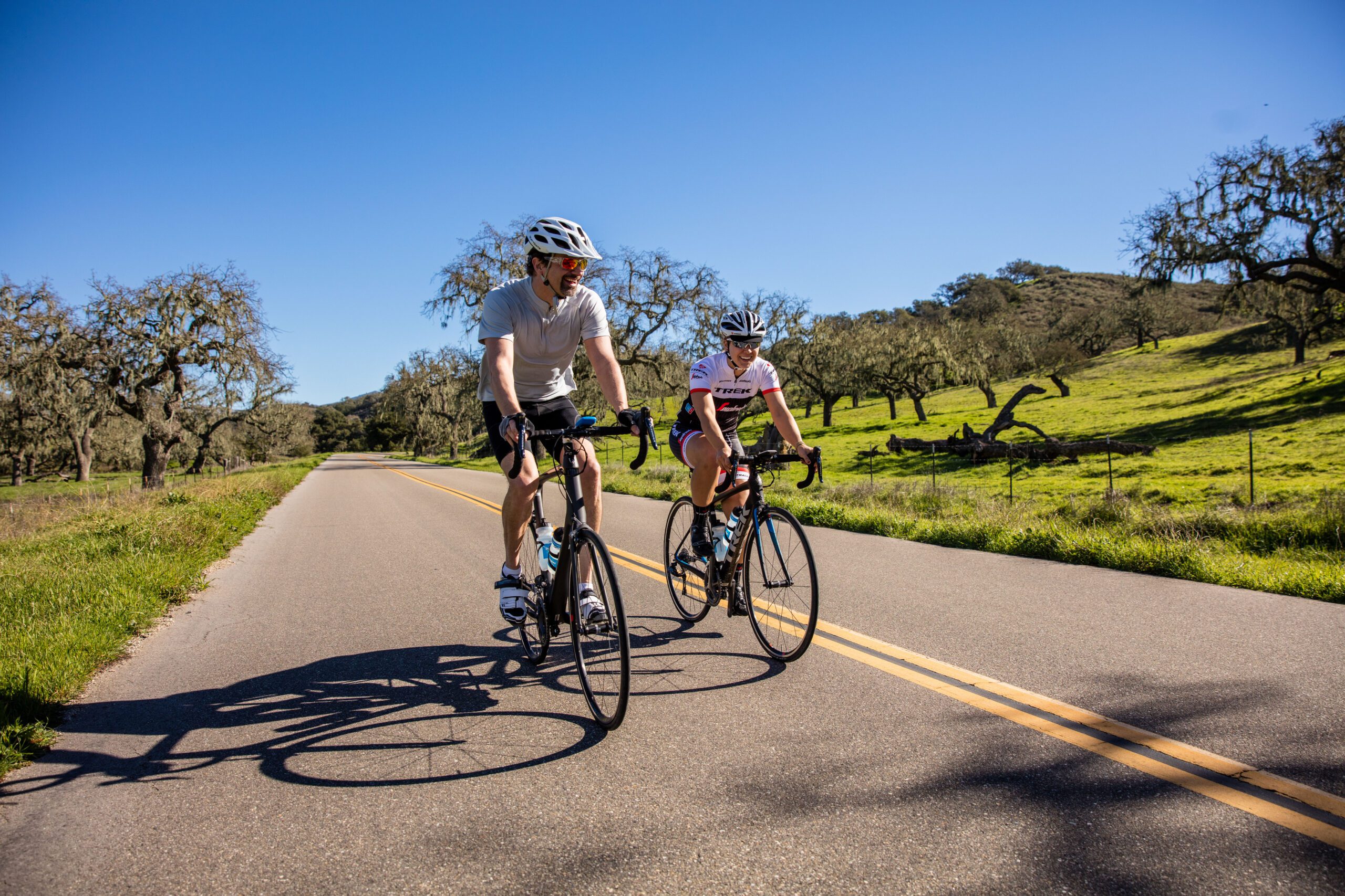 two people riding their bikes smiling on a paved road
