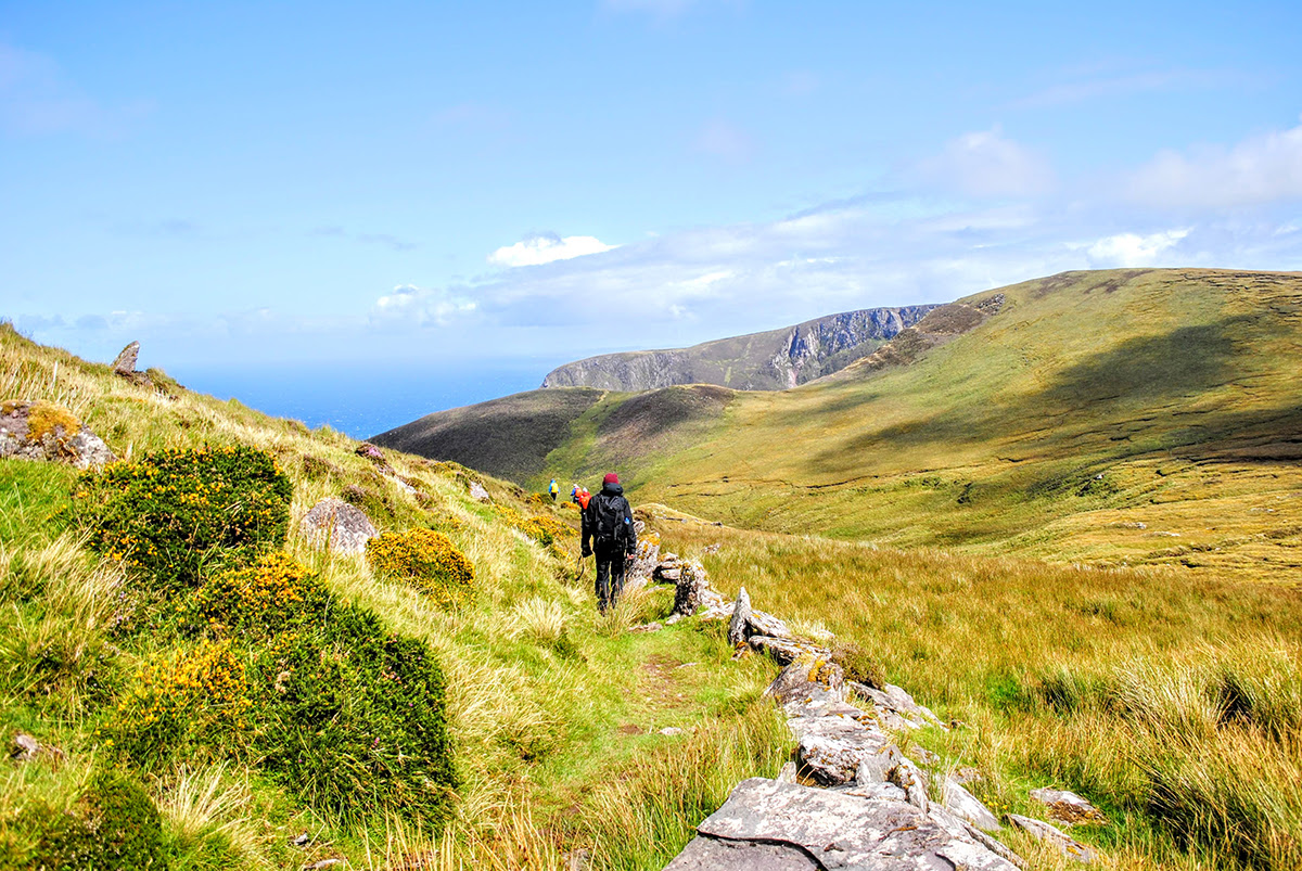 People walking in the green irish landscape near the ocean